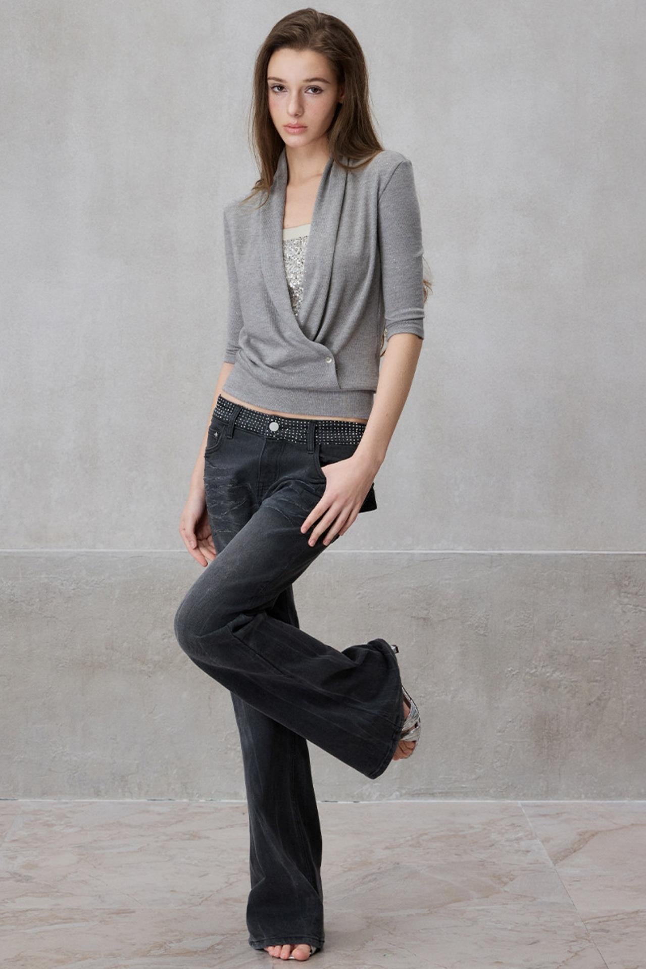 Woman wearing a gray cardigan and black pants against a plain background