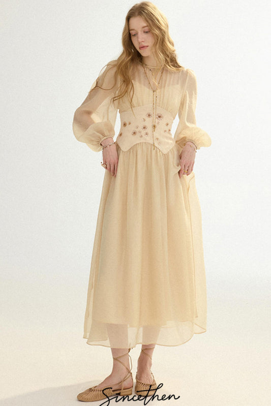 Woman wearing a beige dress with floral embellishments on a white background
