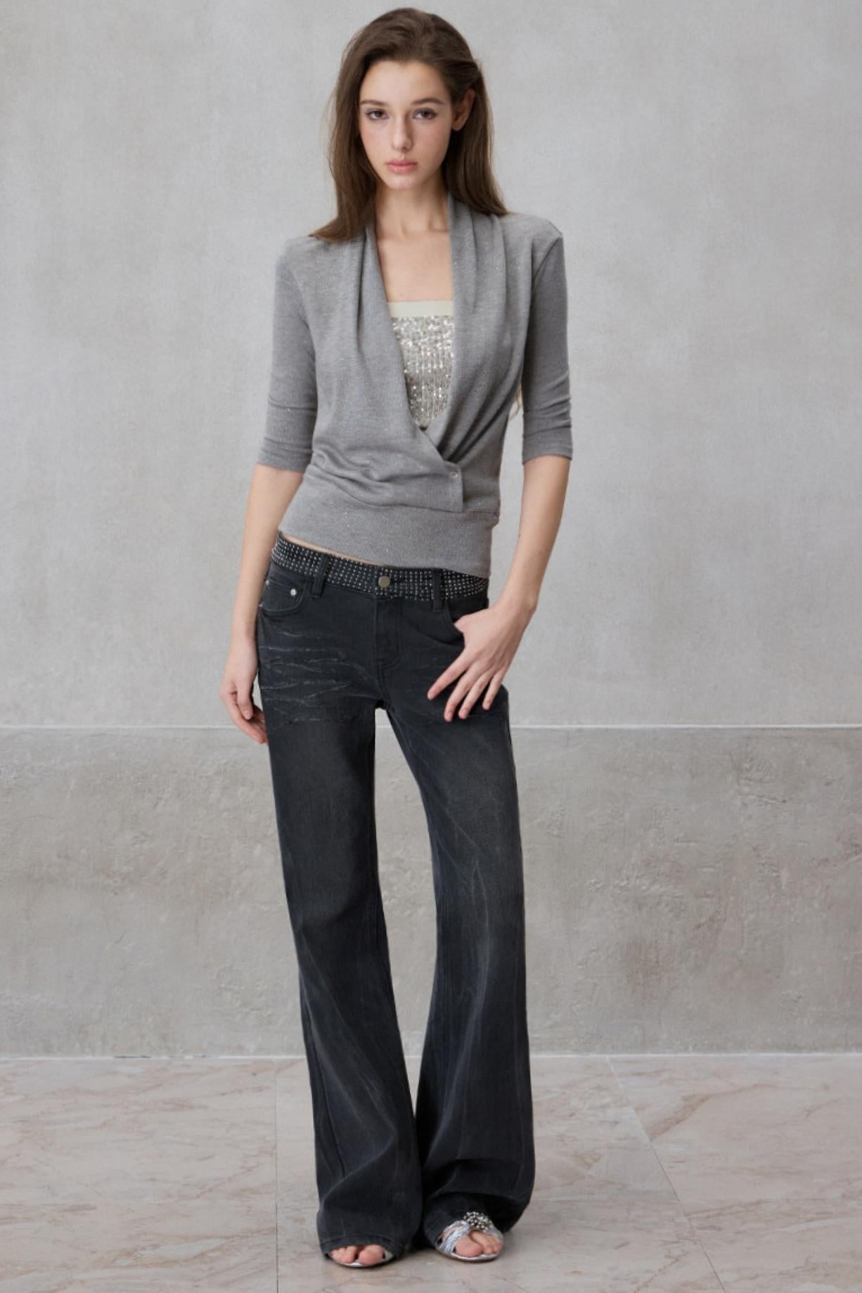 Woman wearing a gray cardigan and black pants against a plain background