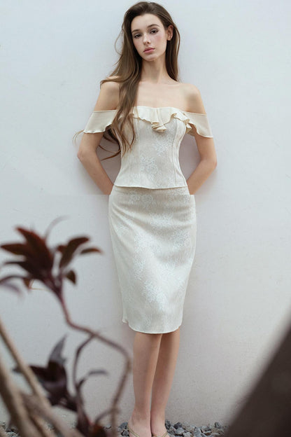 Woman wearing a beige off-shoulder dress against a plain background