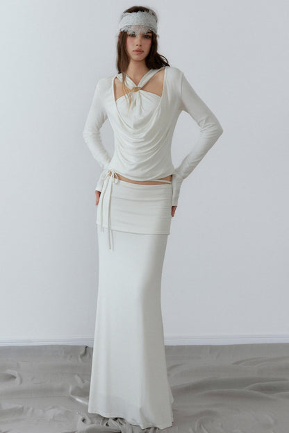 Model showcasing a chic cream long sleeve fake two-piece top featuring a draped cowl neck, halter straps, and a sleek metal knot detail.