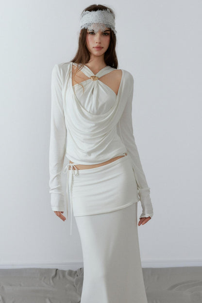Model showcasing a chic cream long sleeve fake two-piece top featuring a draped cowl neck, halter straps, and a sleek metal knot detail.