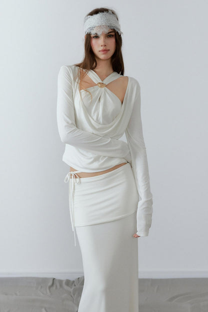 Model showcasing a chic cream long sleeve fake two-piece top featuring a draped cowl neck, halter straps, and a sleek metal knot detail.