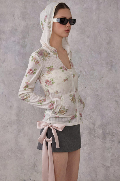 Woman wearing a floral blouse and sunglasses against a gray background