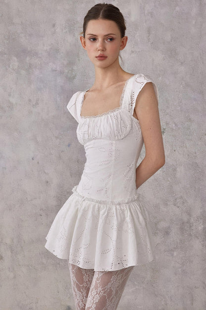 Woman wearing a white lace dress against a gray background