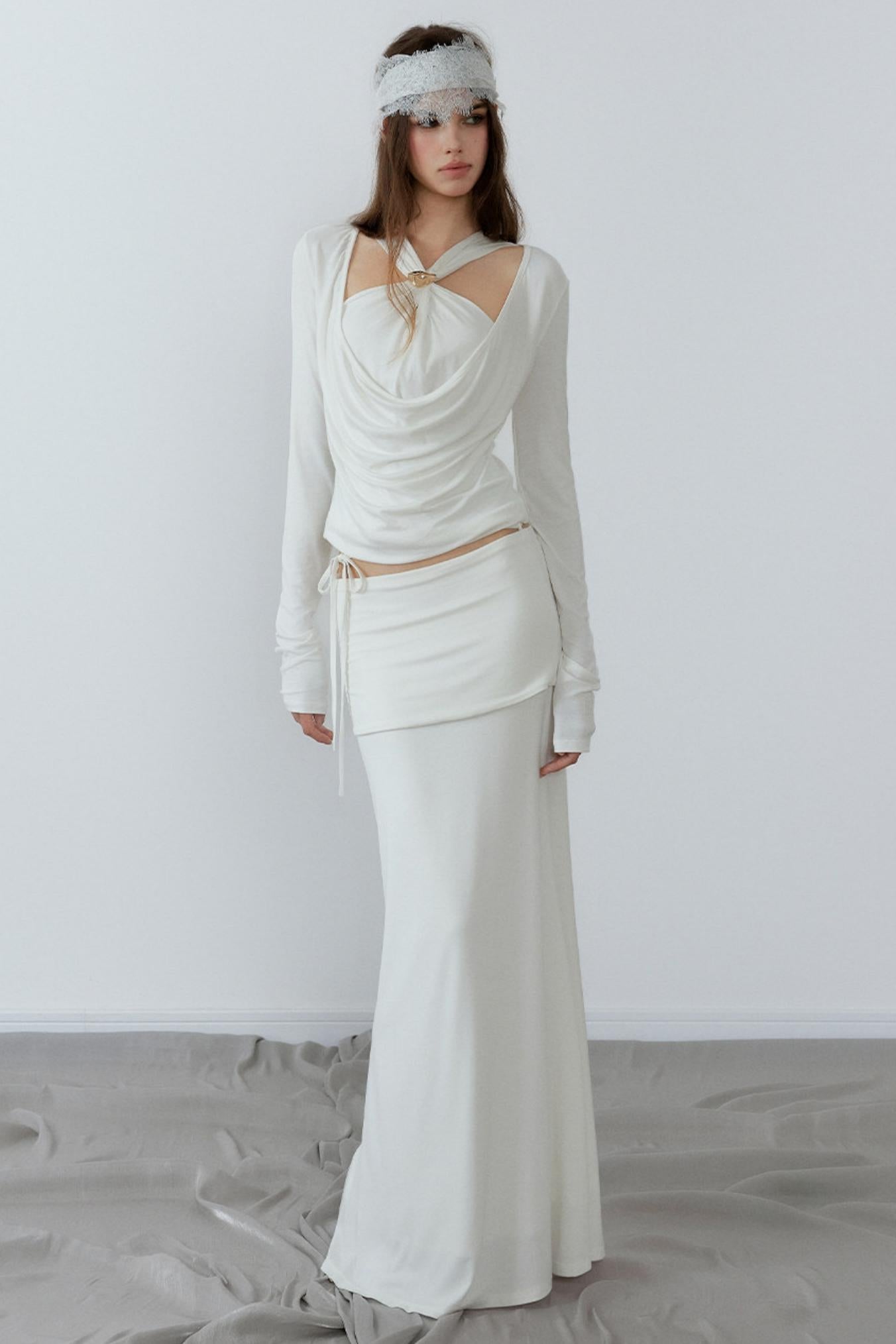 Woman wearing a white outfit with a headband against a plain background