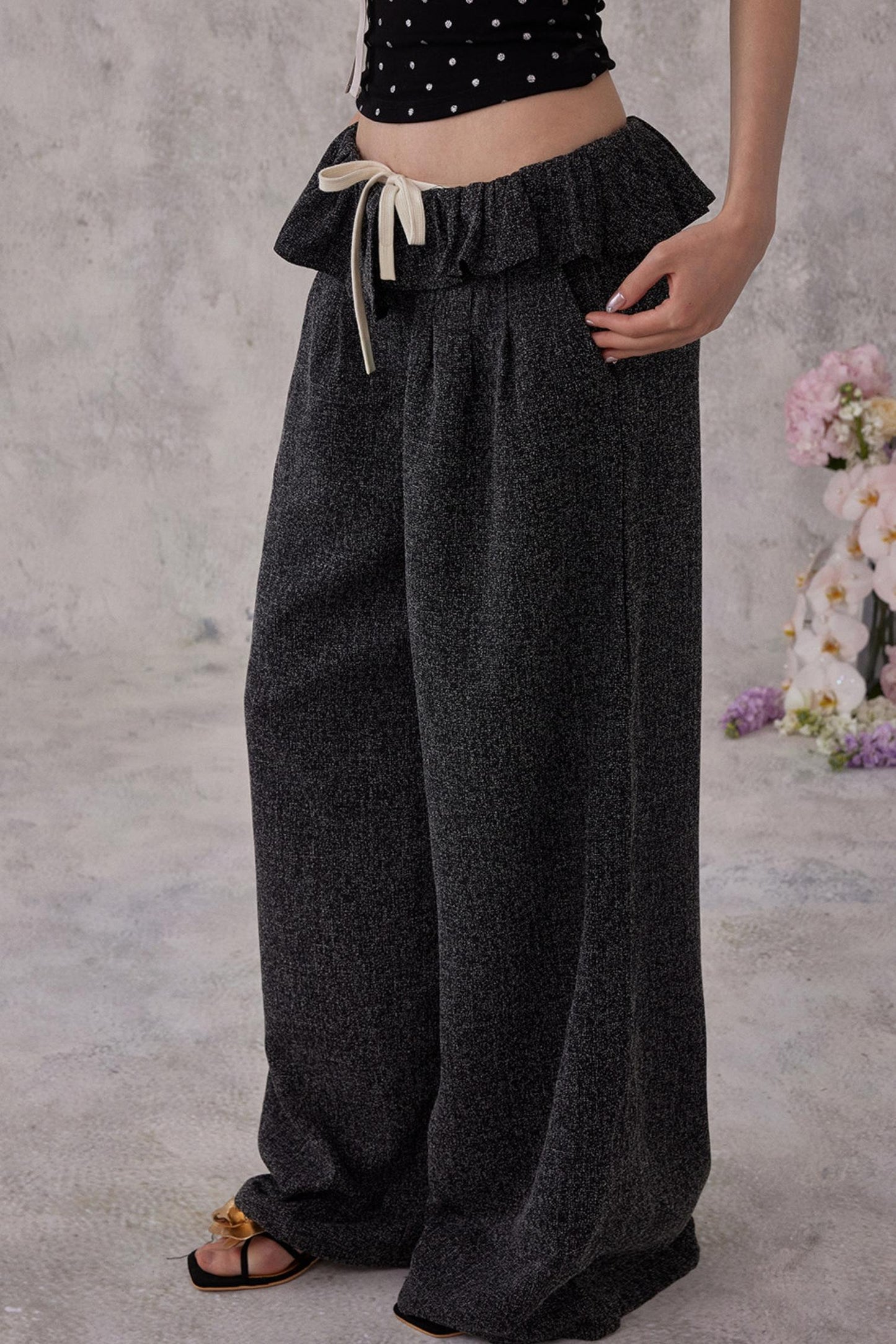 Person wearing dark gray wide-leg pants with a plain background