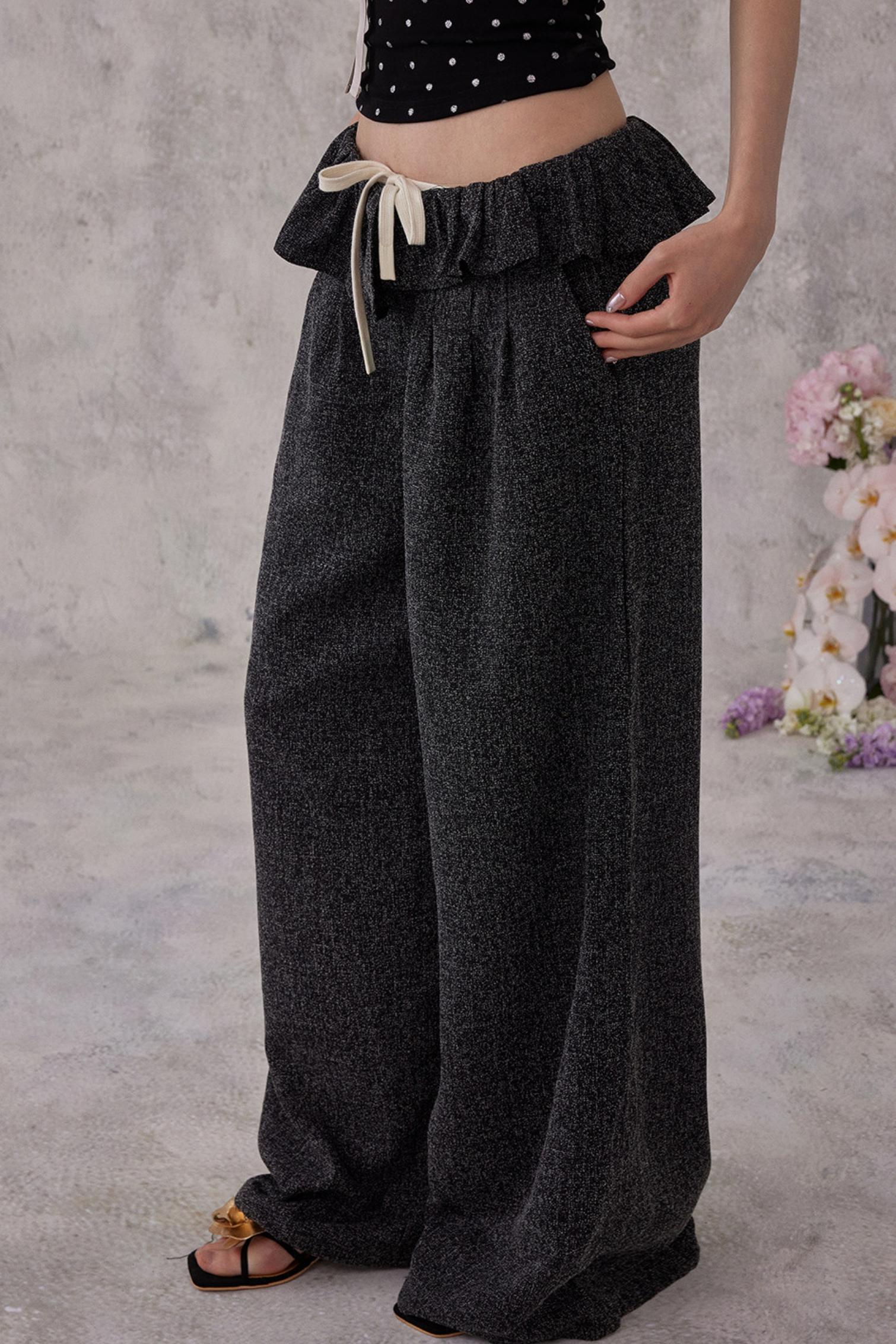 Person wearing dark gray wide-leg pants with a plain background