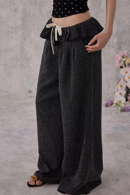Person wearing dark gray wide-leg pants with a plain background
