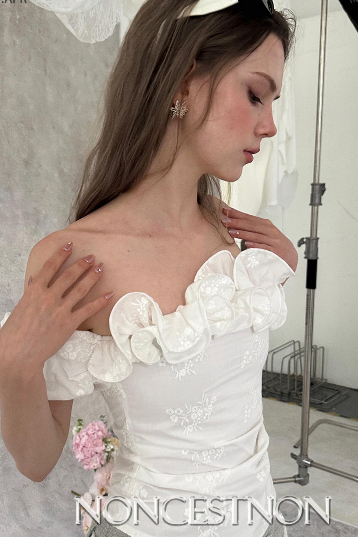 Woman wearing a white lace dress with 'Noncestnon' branding.