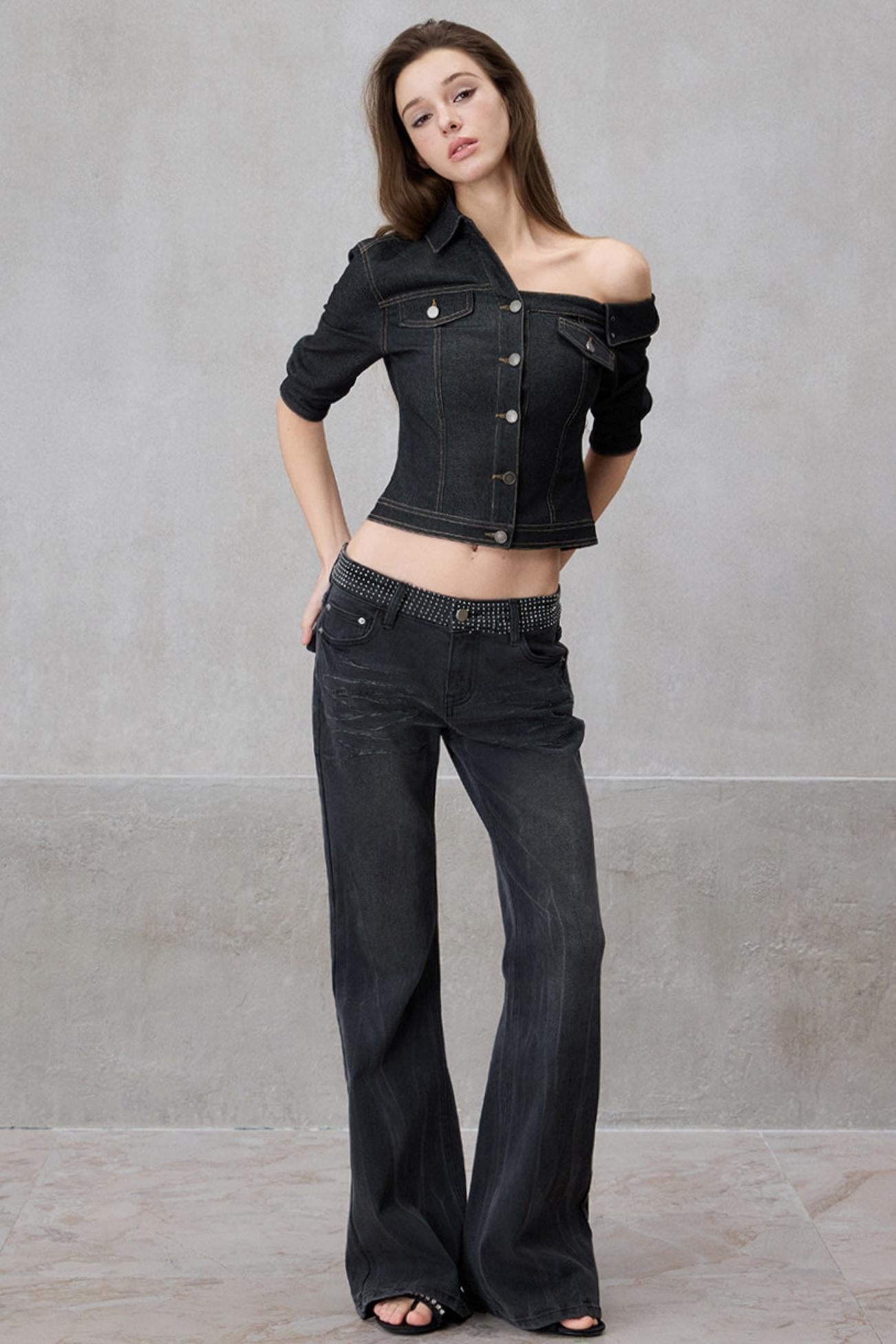 Woman wearing a black denim jacket and jeans against a gray background