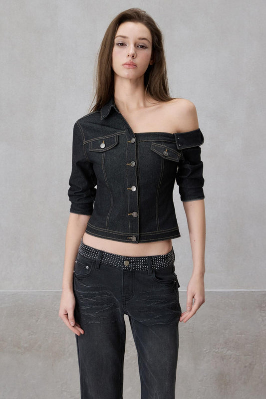 Woman wearing a black denim jacket and jeans against a gray background