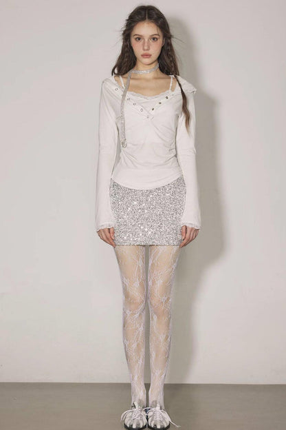 Woman wearing a white outfit with a sequined skirt against a plain background