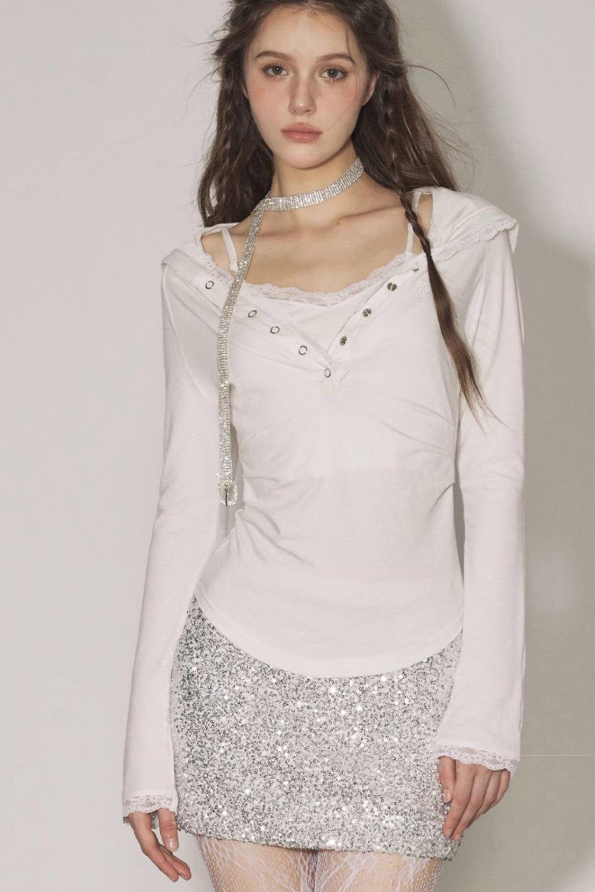 Woman wearing a light pink top and silver sequin skirt against a plain background