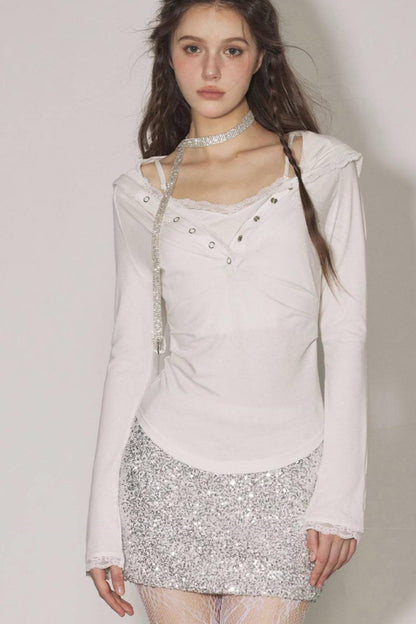 Woman wearing a light pink top and silver sequin skirt against a plain background