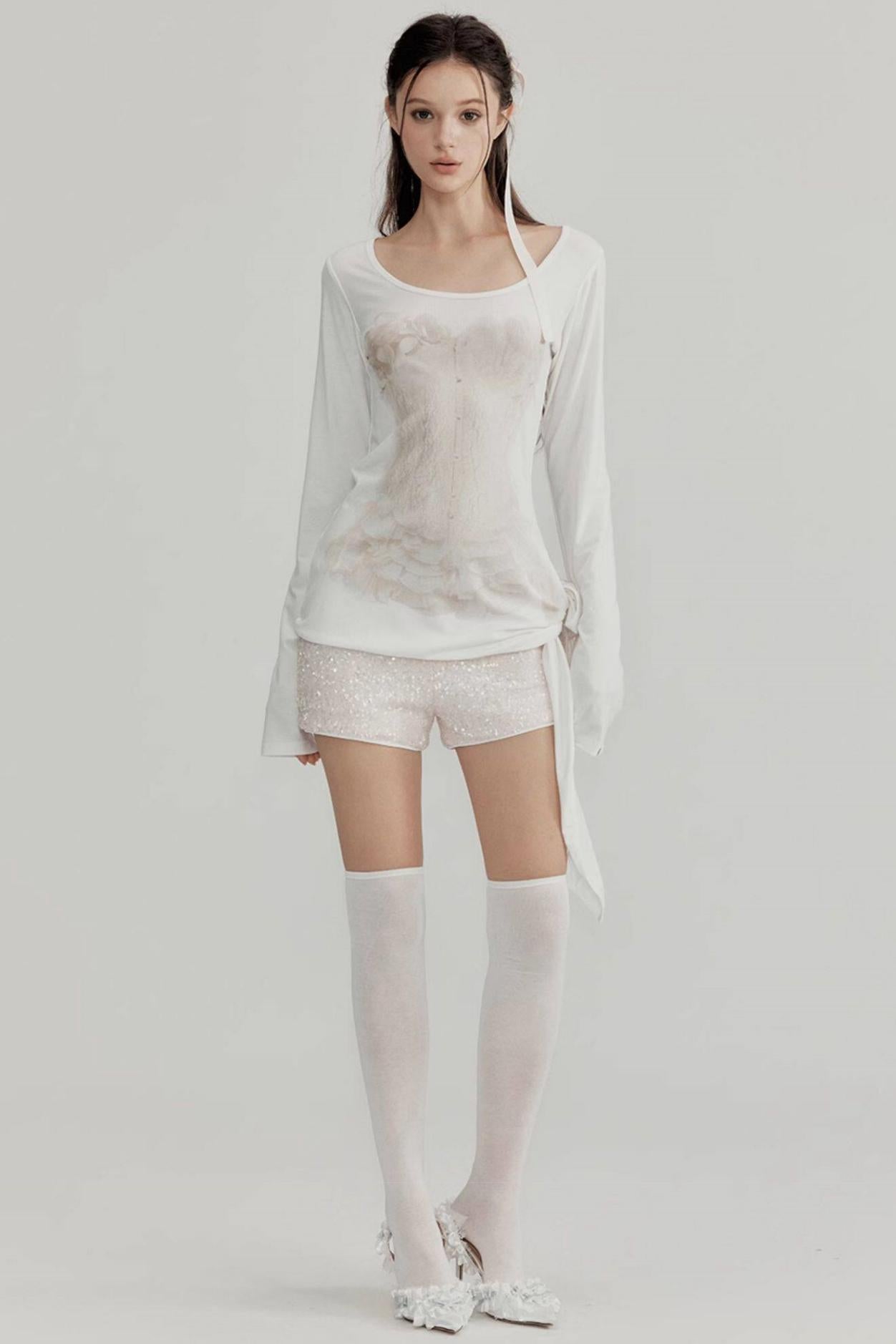 Woman wearing a white outfit with sheer elements on a plain background