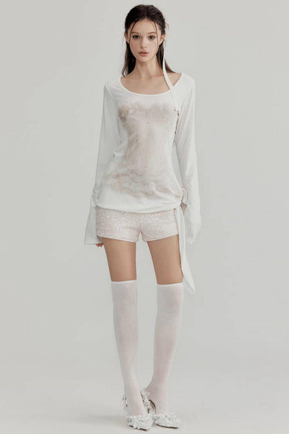 Woman wearing a white outfit with sheer elements on a plain background