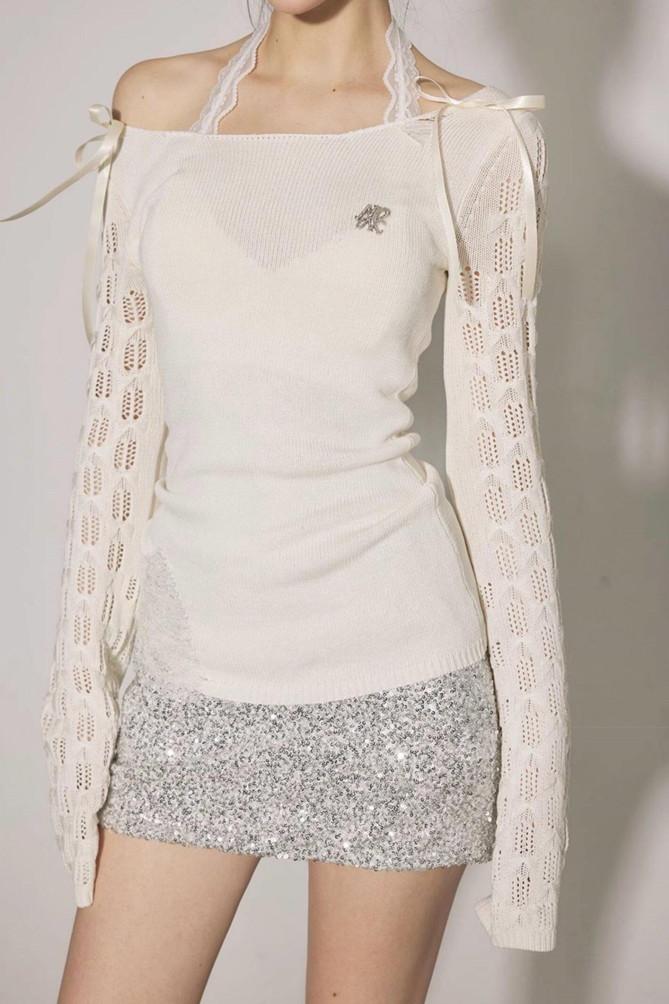 Person wearing a white top and light-colored cardigan with a plain background