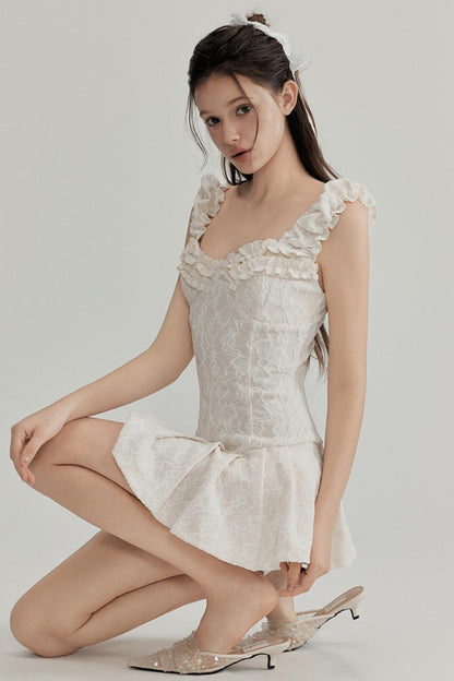 Woman wearing a white lace dress with floral details on a plain background