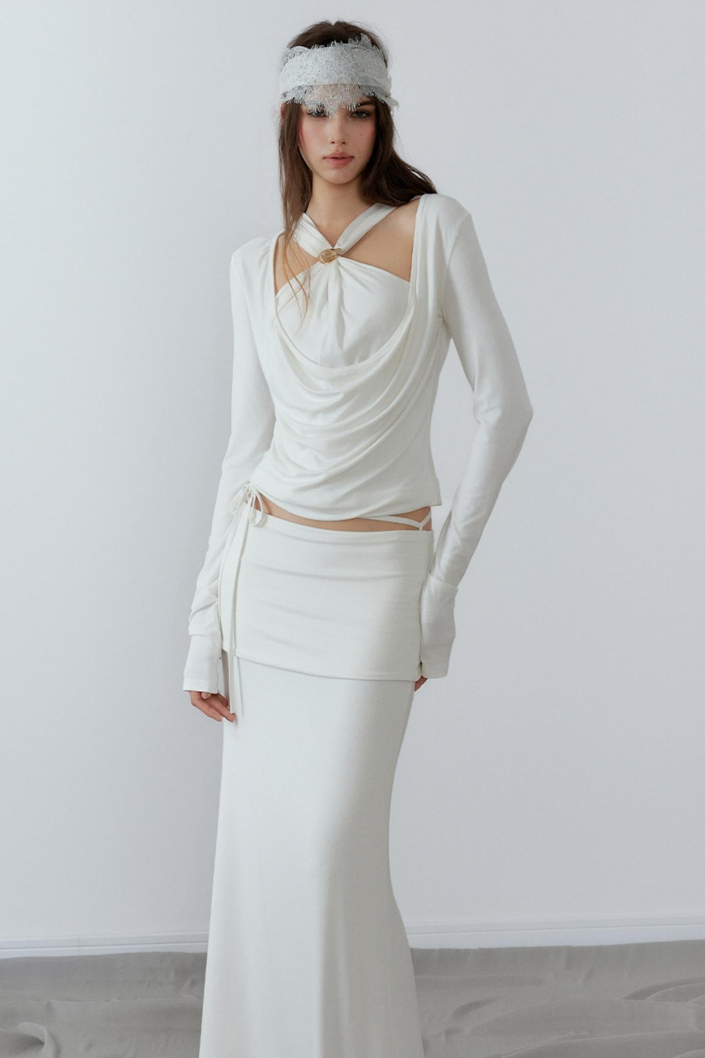 Model showcasing a chic cream long sleeve fake two-piece top featuring a draped cowl neck, halter straps, and a sleek metal knot detail.
