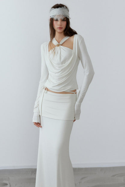 Model showcasing a chic cream long sleeve fake two-piece top featuring a draped cowl neck, halter straps, and a sleek metal knot detail.