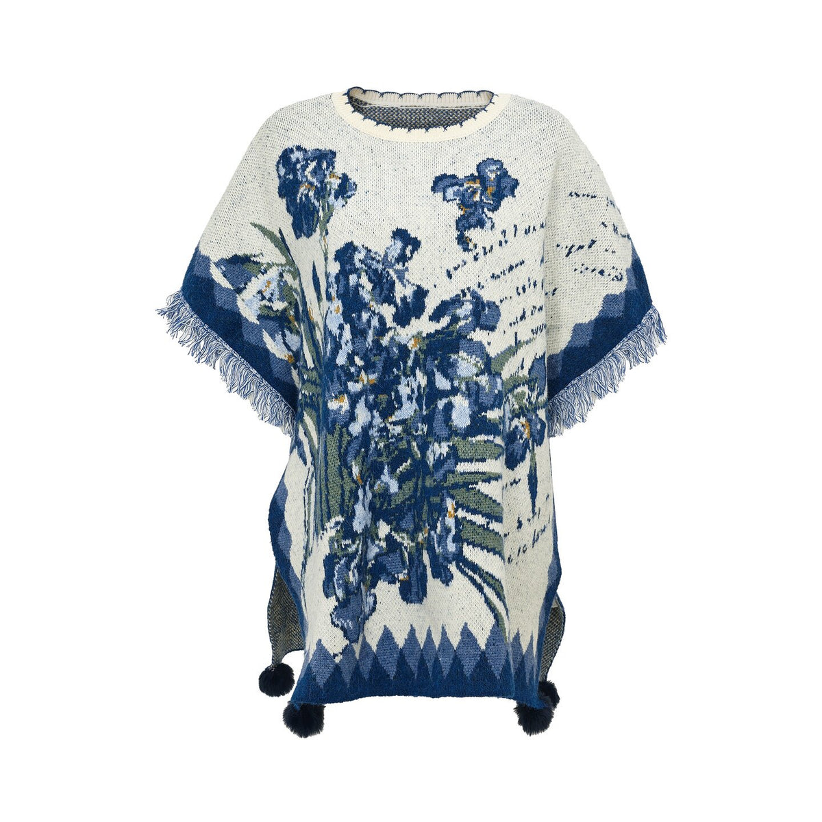 A cream-colored knit poncho sweater featuring a blue and green floral pattern, fringed edges, and pom-poms at the bottom, displayed on a white background.
