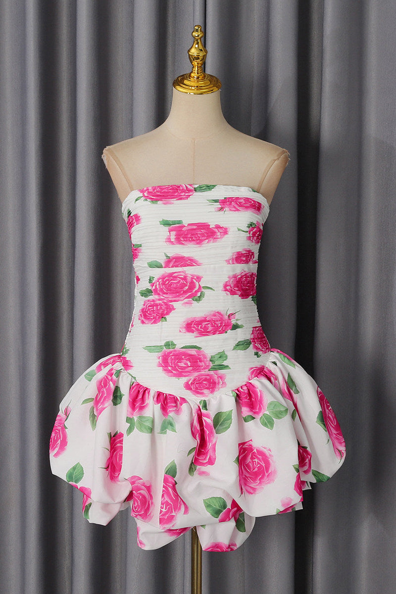 A strapless white dress with a vibrant pink rose and green leaf pattern, displayed on a beige mannequin dress form against a gray curtain backdrop.