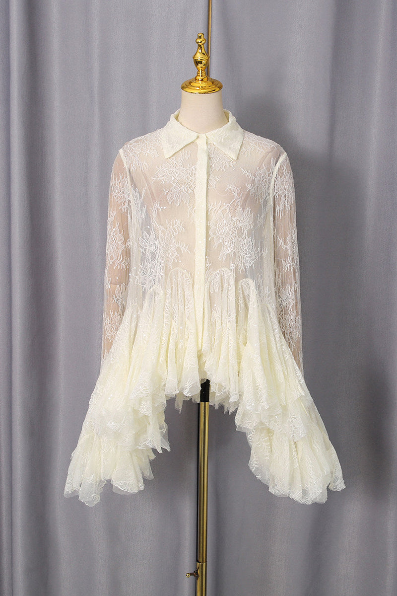 An ivory lace long-sleeve blouse with a ruffled tiered hem, displayed on a cream mannequin torso with a gold stand against a gray curtain backdrop.