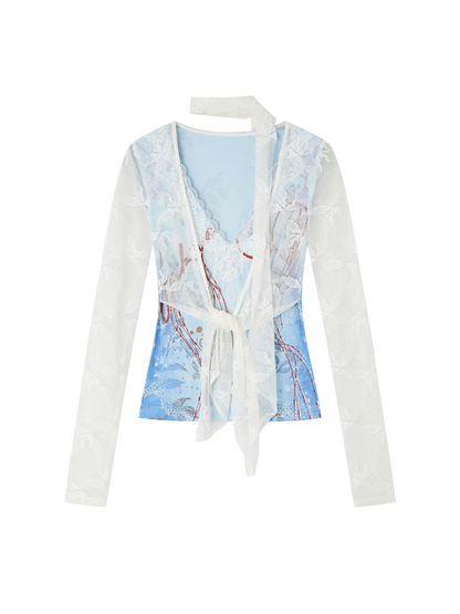 A women's long-sleeve wrap top featuring a light blue printed body with white floral lace overlays and a white tie-front waist, shown on a plain white background.