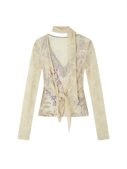A beige long-sleeve wrap-style blouse with a tie-front waist and a matching neck tie, featuring a subtle tonal floral jacquard pattern with lavender and gold undertones, shown on a plain white background.