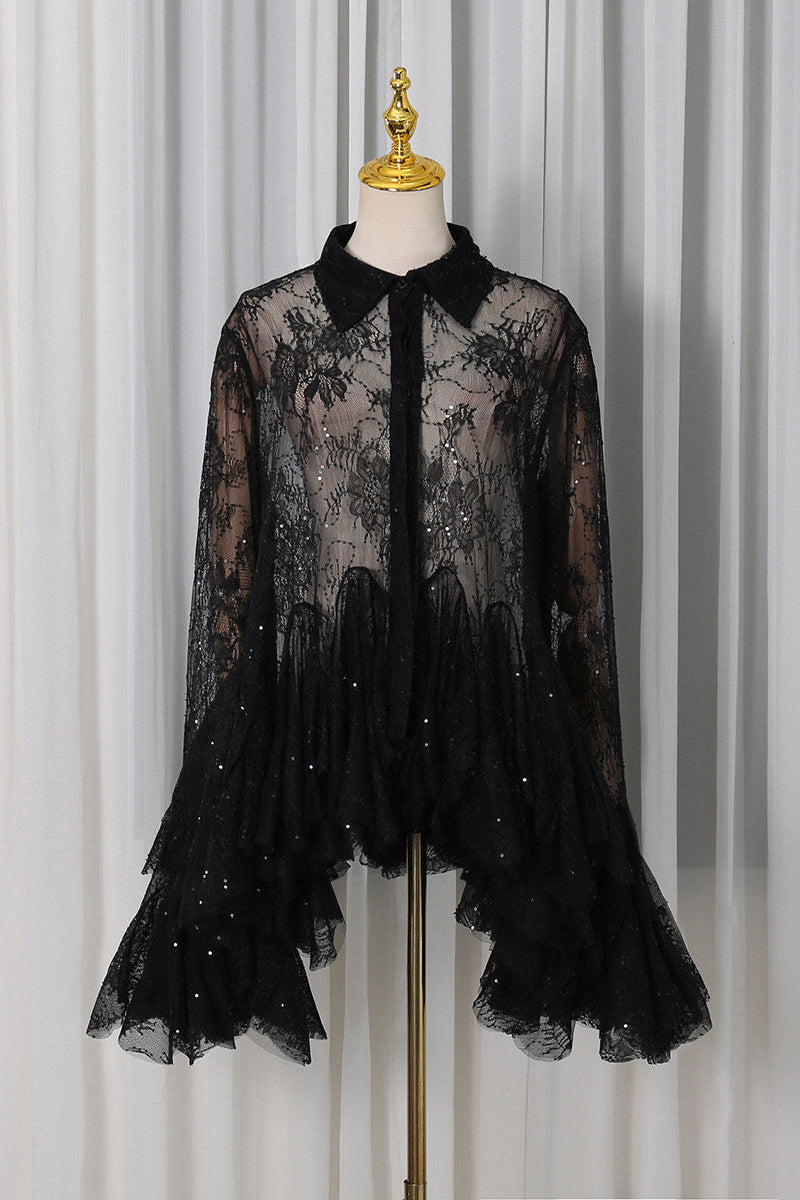 A black sheer lace blouse with a pointed collar, long sleeves, and a ruffled tiered hem embellished with small sequins, displayed on a mannequin torso against a white curtain backdrop.