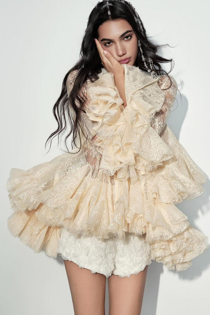 A model wearing a cream-colored, heavily ruffled tulle top with matching textured shorts, posed against a plain white studio background.