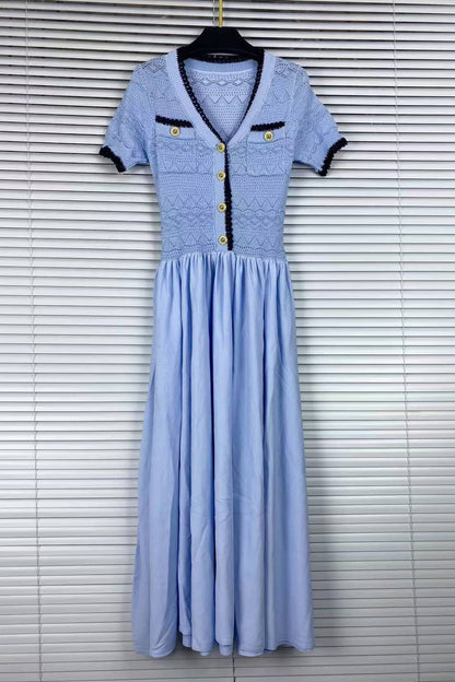 A light blue midi dress with a lace bodice, short sleeves, and gold buttons, hanging on a black hanger against a white window blind background.