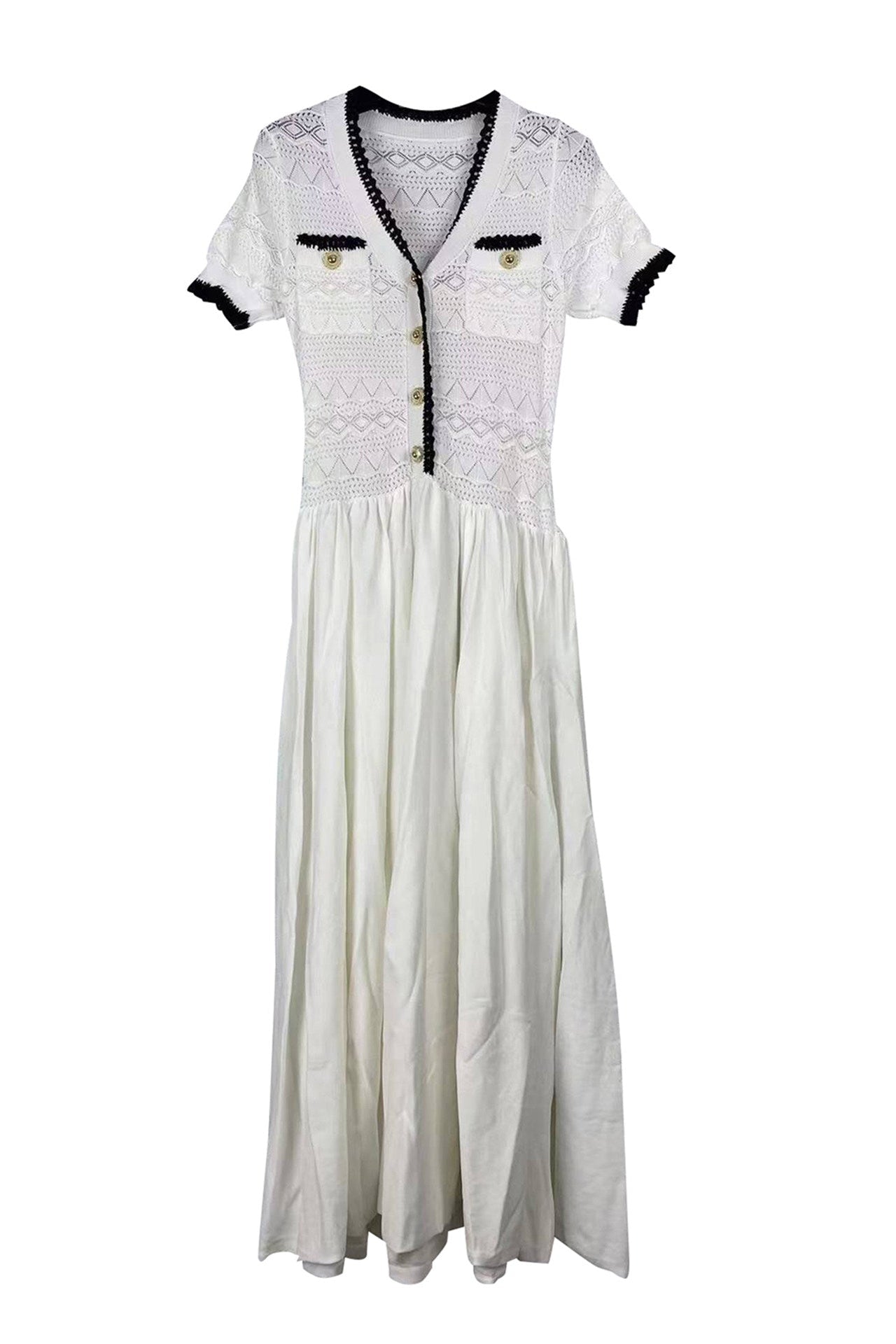 A white maxi dress featuring a textured crochet bodice with black trim, short sleeves with black cuffs, and a gathered skirt, displayed against a solid white background.