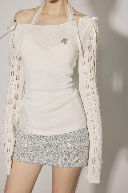 Person wearing a white top and silver skirt with a light-colored cardigan.
