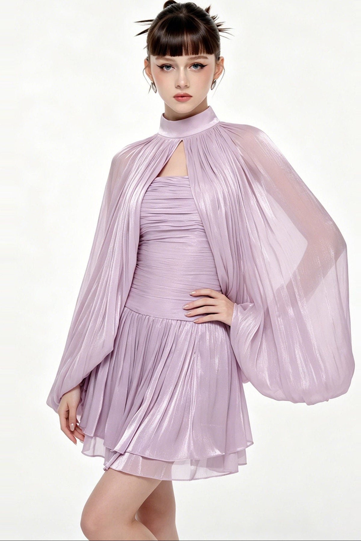 A model wearing a shiny lavender pleated dress with a matching high-neck sheer cape jacket, set against a plain white studio background.