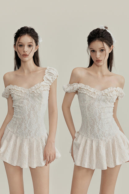 Two women wearing off-shoulder lace dresses on a plain background