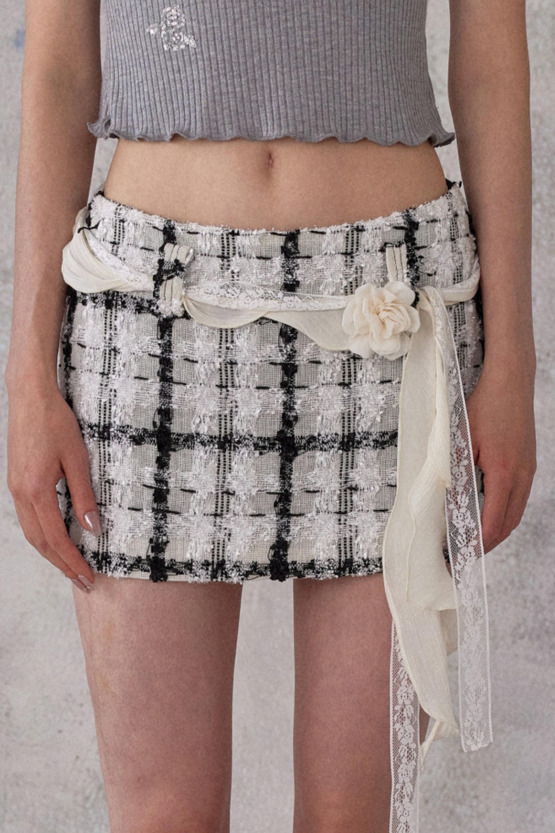 Person wearing a black and white checkered skirt with a plain background