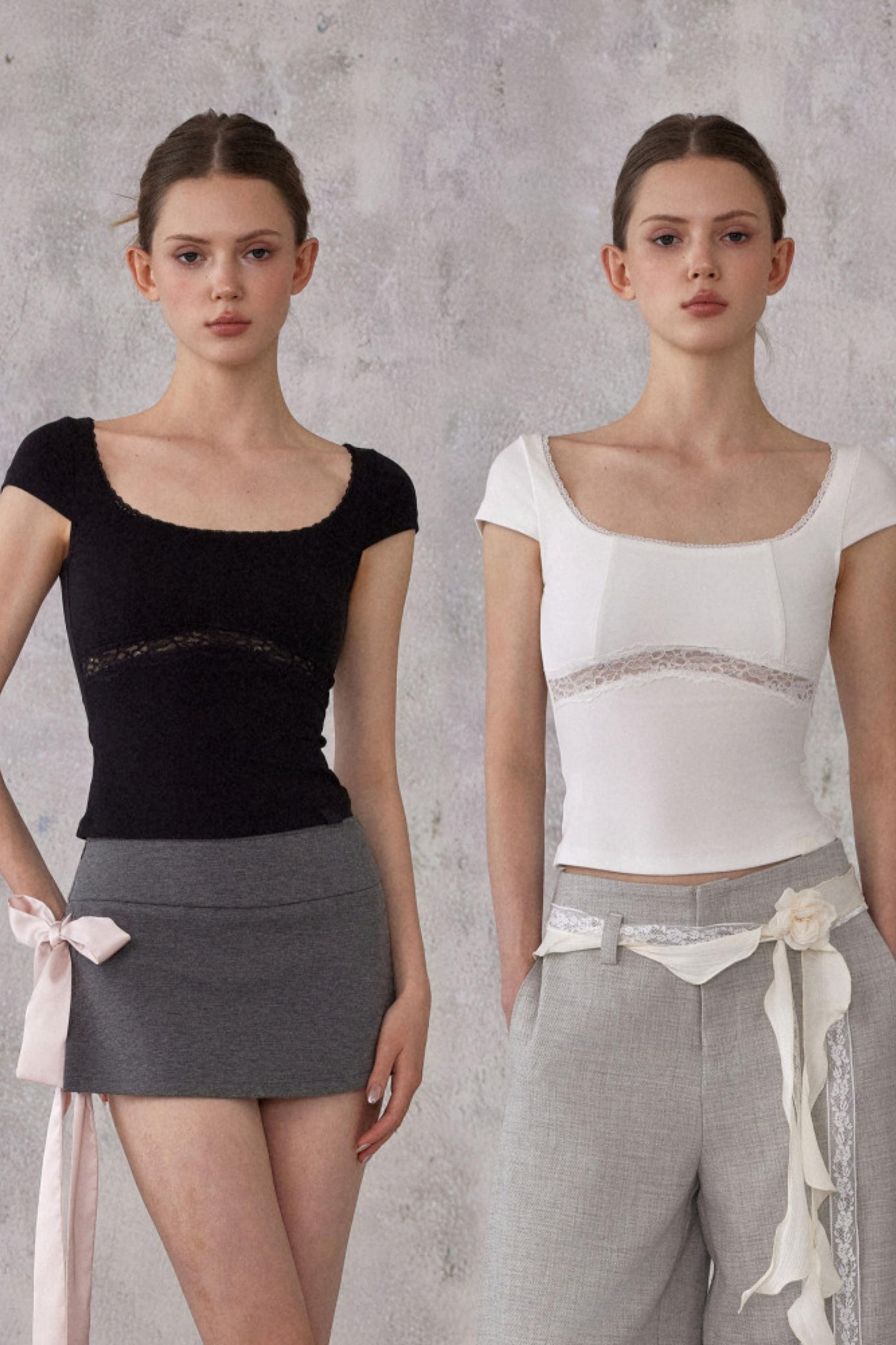 Two models wearing black and white tops with gray skirts against a gray background