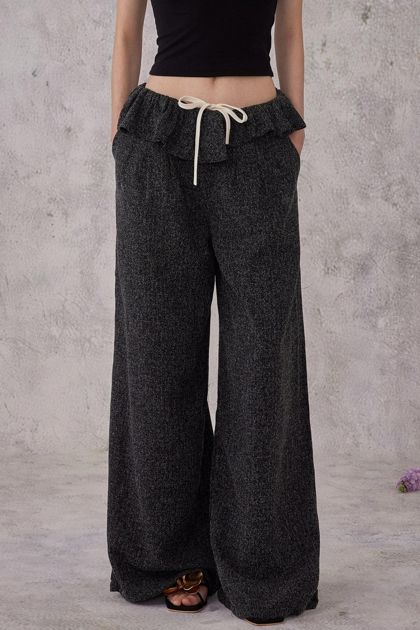 Person wearing dark gray wide-leg pants with a plain background