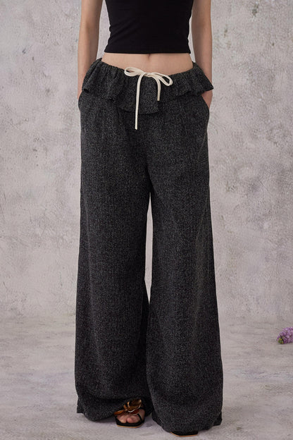 Person wearing dark gray wide-leg pants with a plain background