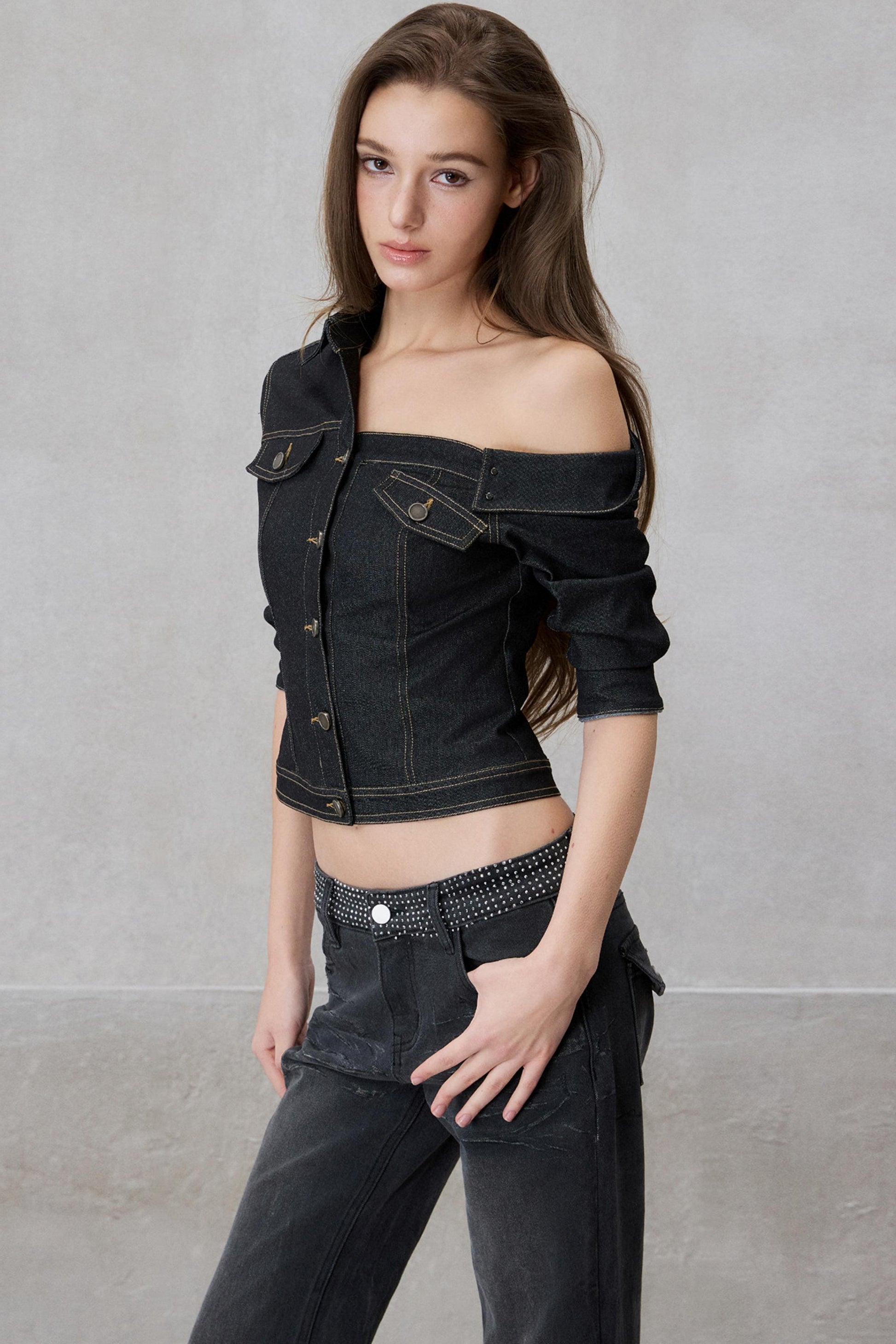 Woman wearing a black denim jacket and pants against a gray background