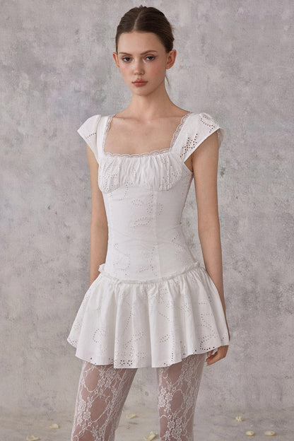 Model wearing a white lace dress against a gray background