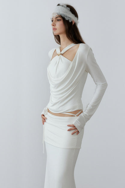 Model showcasing a chic cream long sleeve fake two-piece top featuring a draped cowl neck, halter straps, and a sleek metal knot detail.