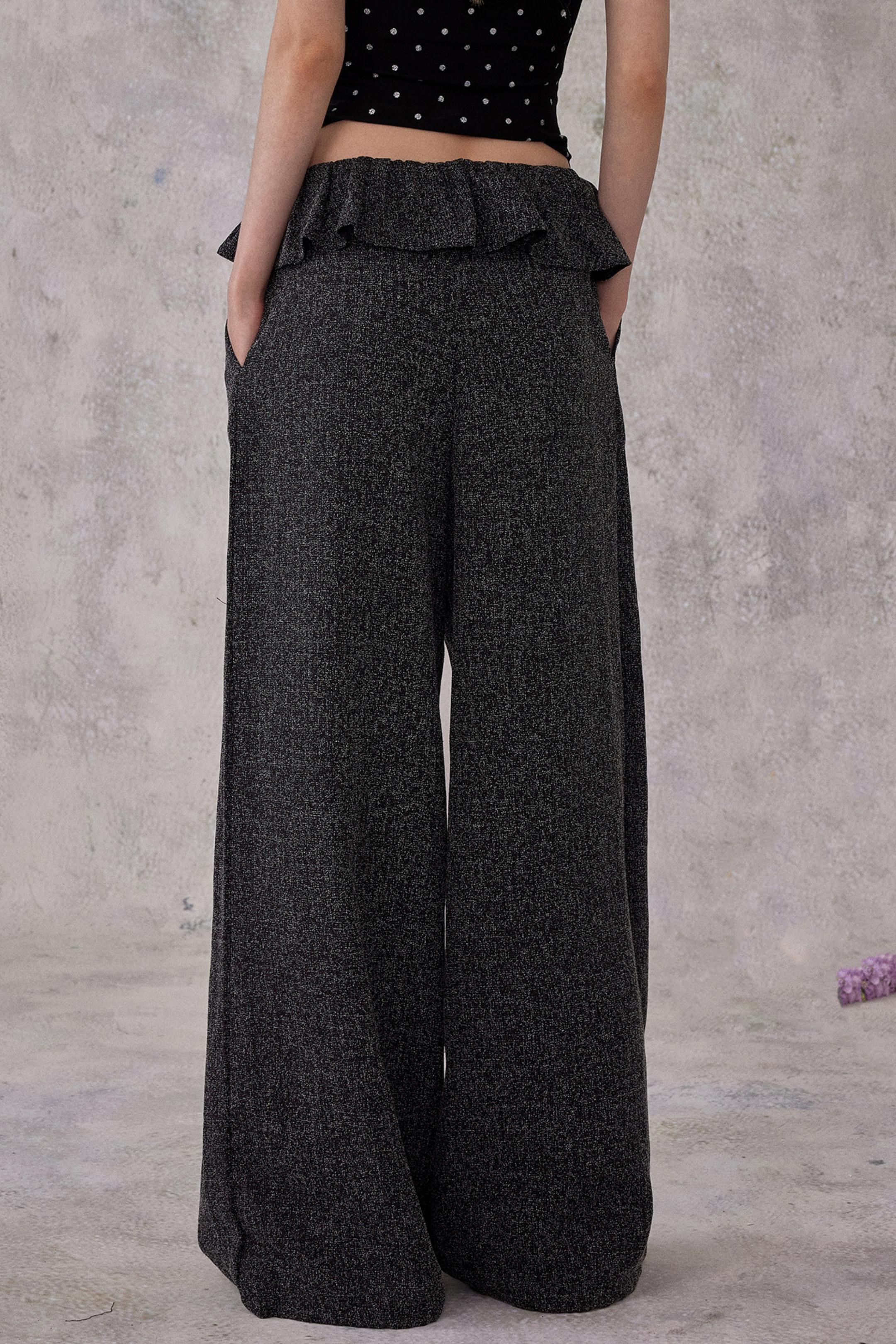 Person wearing dark gray wide-leg pants against a plain background