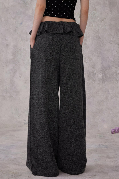 Person wearing dark gray wide-leg pants against a plain background