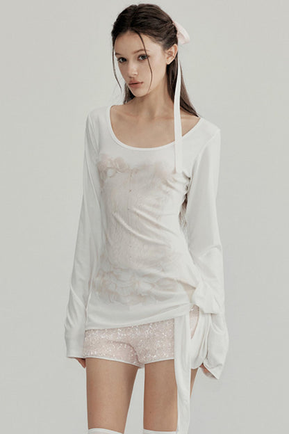 Woman wearing a white outfit with sheer overlay on a plain background