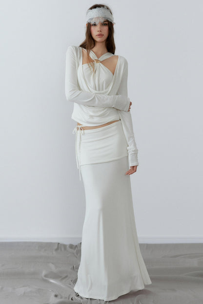 Woman wearing a white dress with long sleeves and a headband against a plain background