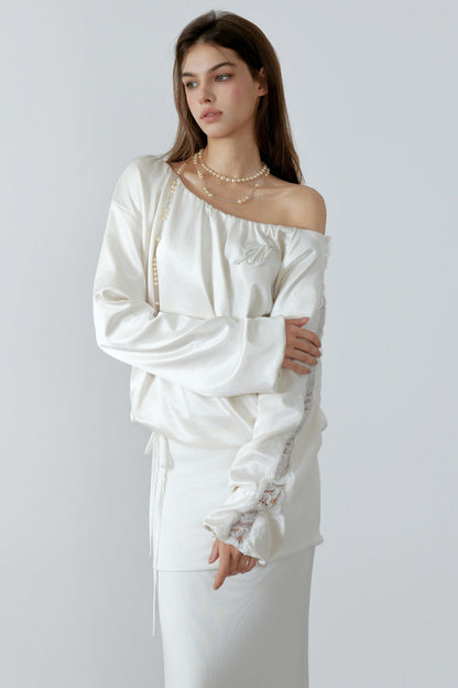 Woman wearing a white off-shoulder dress with lace details on a plain background