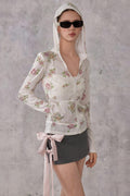 Model wearing a slim-fit floral print pointelle knit hooded cardigan with ribbon details, paired with a dark mini skirt.